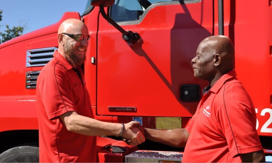 Two CDL-A licensed MVL truck drivers shaking hands in front of an MVL truck cab