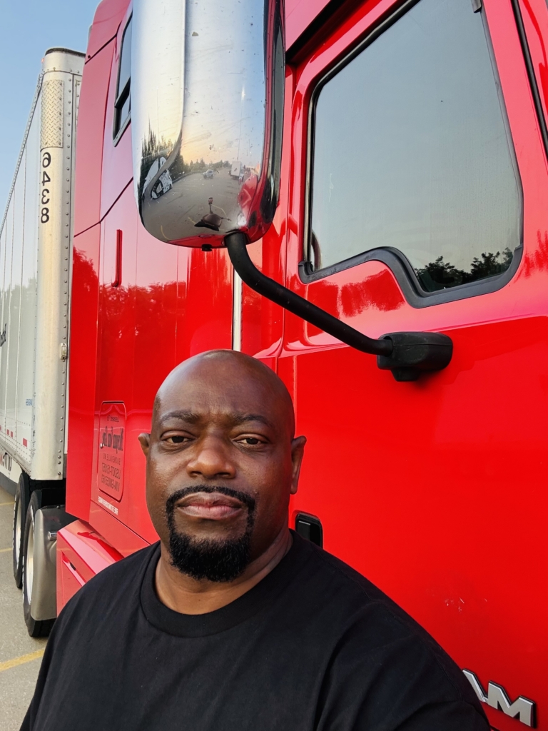 Arlando Rutherford standing beside his red truck